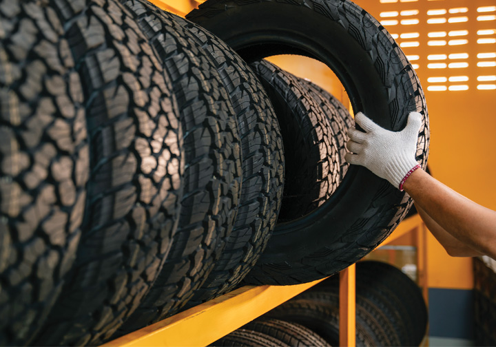 Someone takes a tyre off a rack of tyres. 