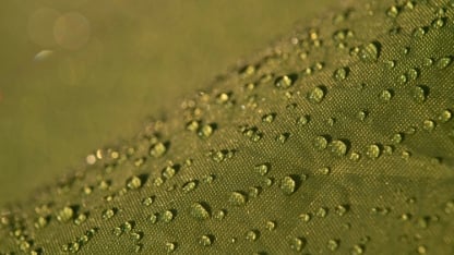 Water droplets on waterproof fabric.Water drops on a green waterproof fabric close-up macro photography.Water drops on a waterproof fabric. ( Water droplets on the tent fabric.)	