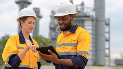 Two electrical plant engineers discuss power usage using a tablet