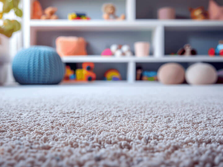 White carpet in children's playroom with shelves of toys in the background