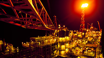image of oil rig at night, lit by flare